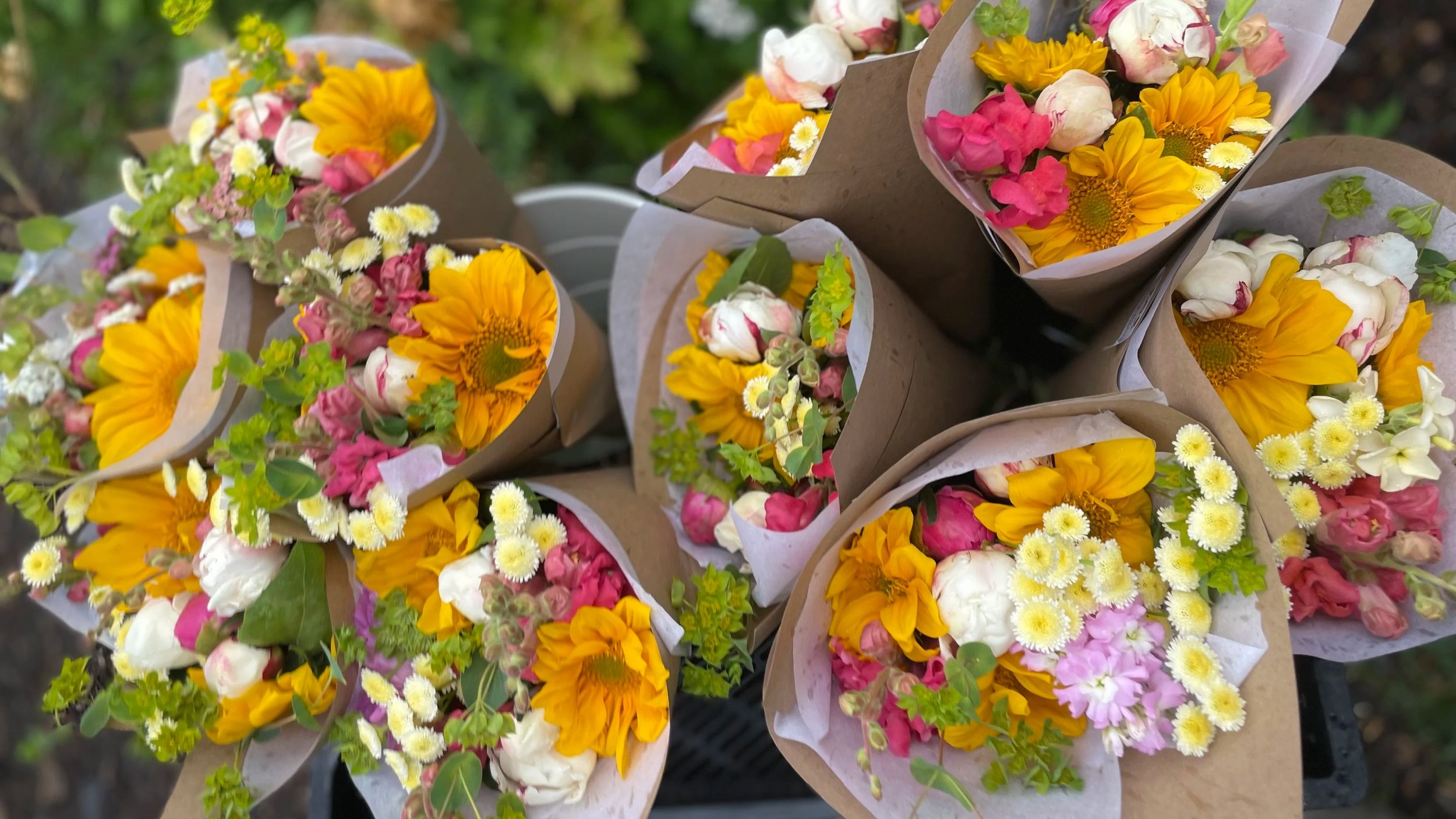 Colorful flower bouquets featuring sunflowers, peonies, and assorted seasonal blooms wrapped in eco-friendly paper. Perfect for gifting or home decoration.